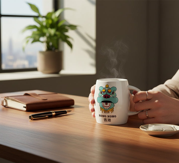 Lizfrydesign white ceramic mug with a teal and yellow lion dance head graphic and "Hong Kong" text.